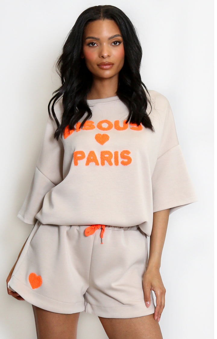 a beige T-shirt  and shorts set with orange text and accents 