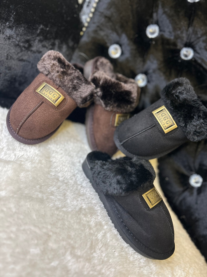 a choice of chocolate brown or black closed toe slip on faux fur slippers with gold buckle on the front
