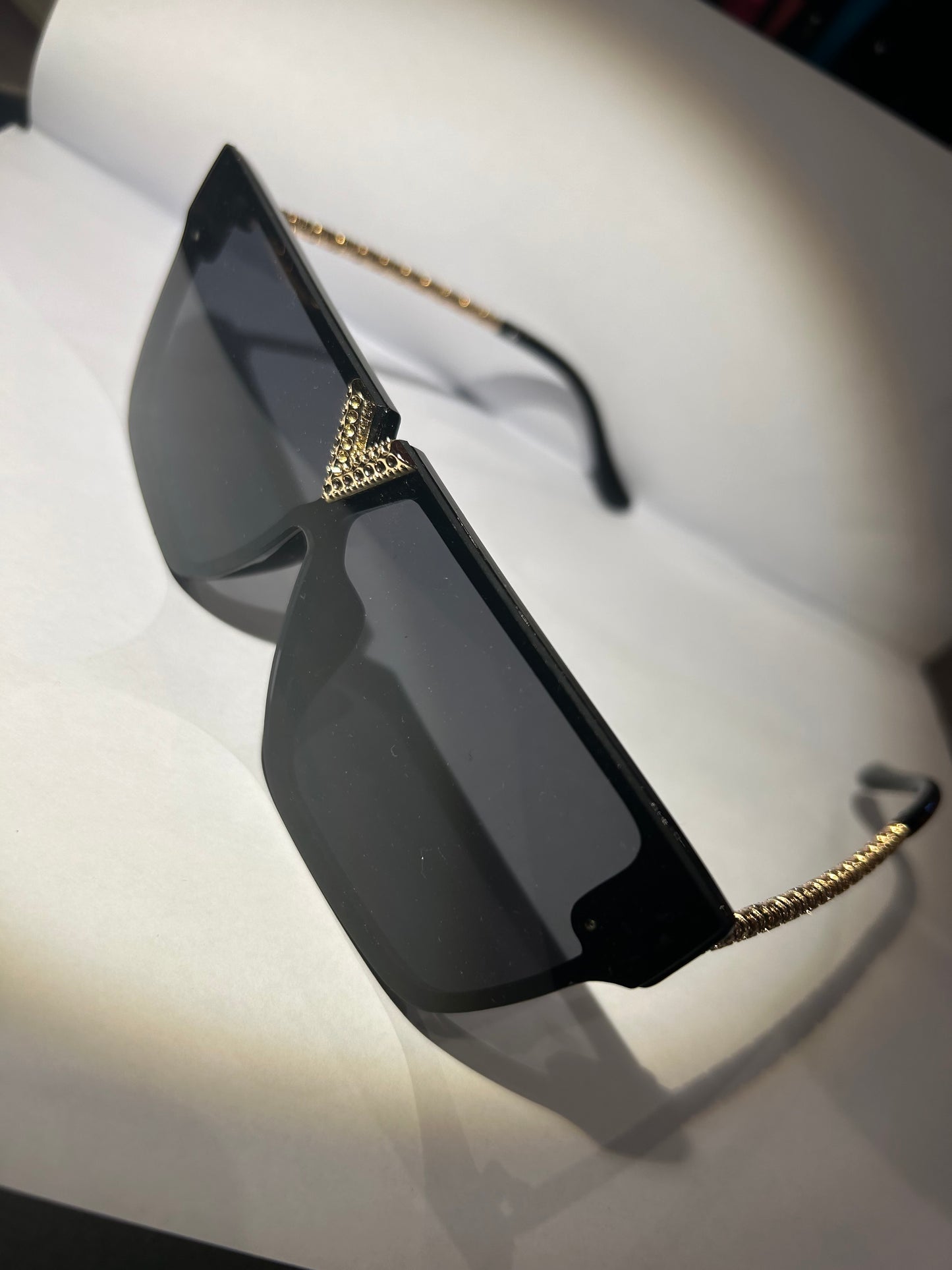 A pair of black sunglasses with gold detailing on the arms.