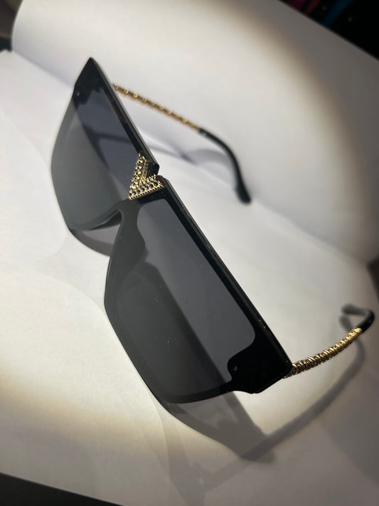 A pair of black sunglasses with gold detailing on the arms.