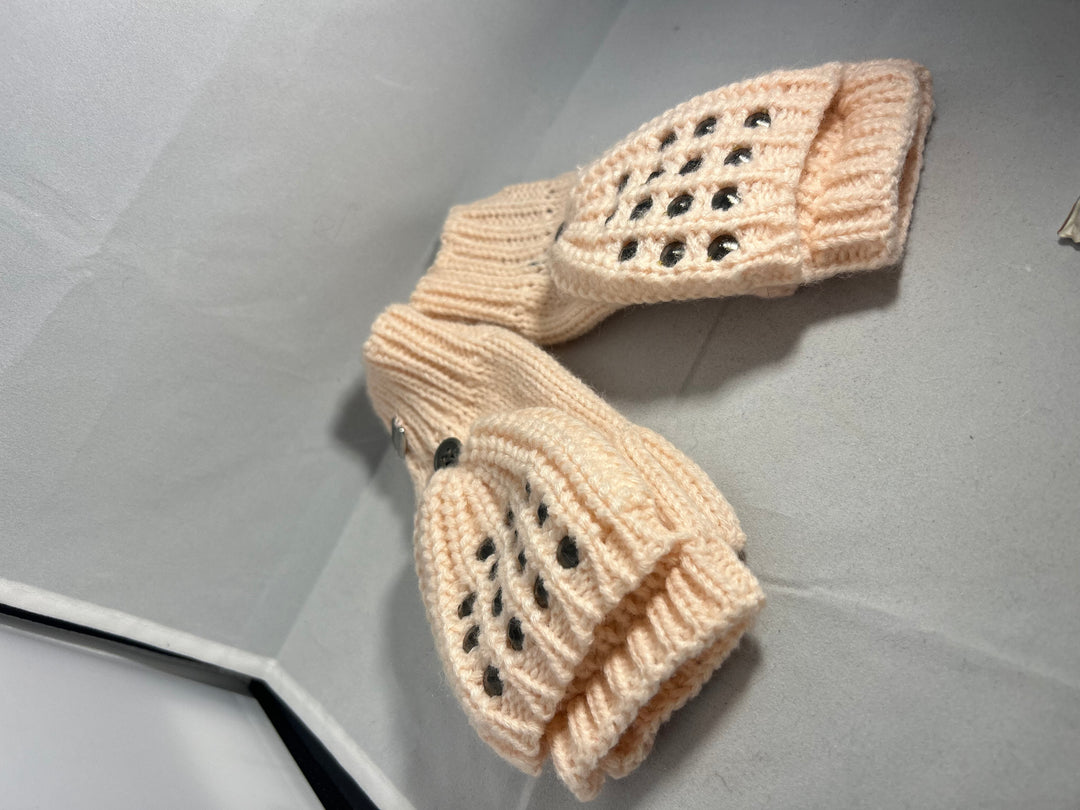 A pair of baby pink knitted mittens with stud patterns
