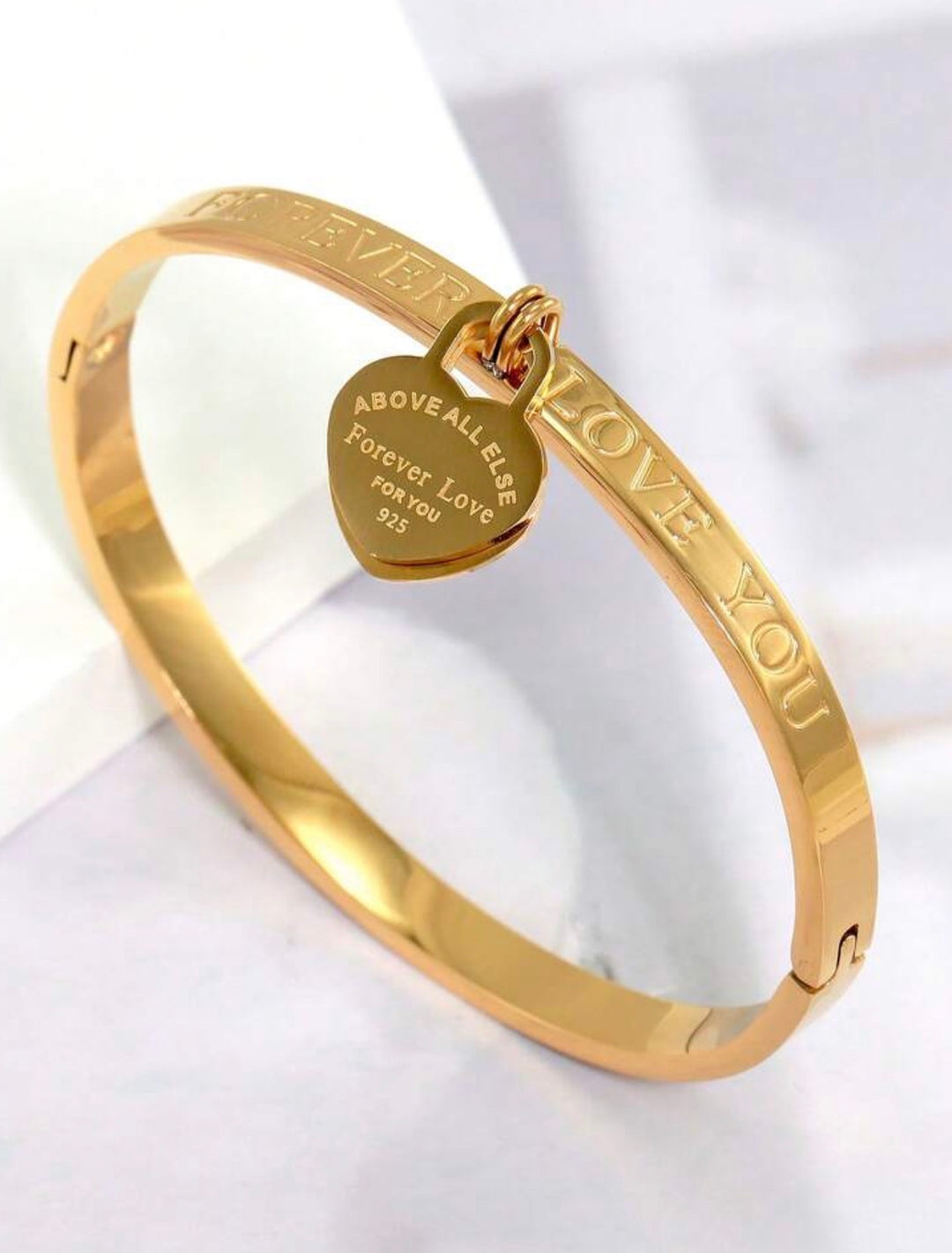     Gold three-piece stainless steel love bangle bracelet set with heart charms and crystal detailing.