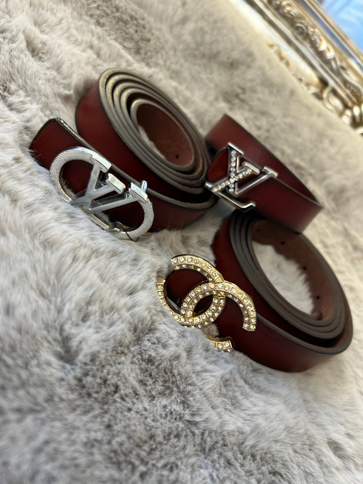 A collection of small brown belts with different buckles