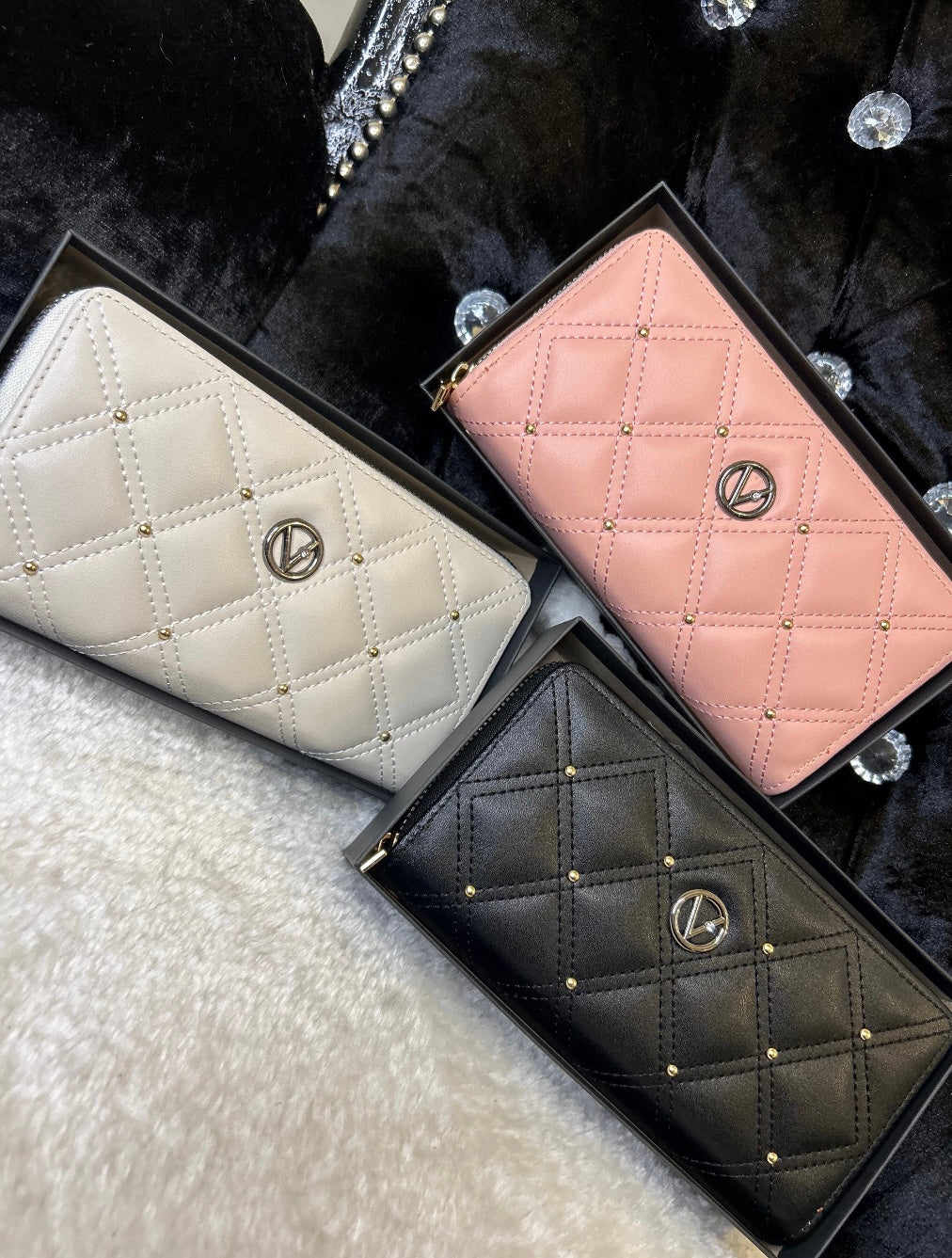 Three quilted leather purses in pink, white, and black, displayed side by side with zip compartments visible.