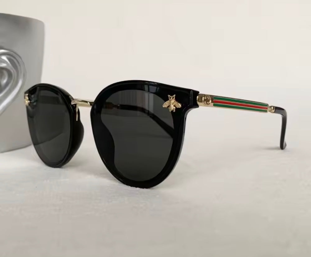 Black sunglasses with gold bee embellishment and green red stripe arms