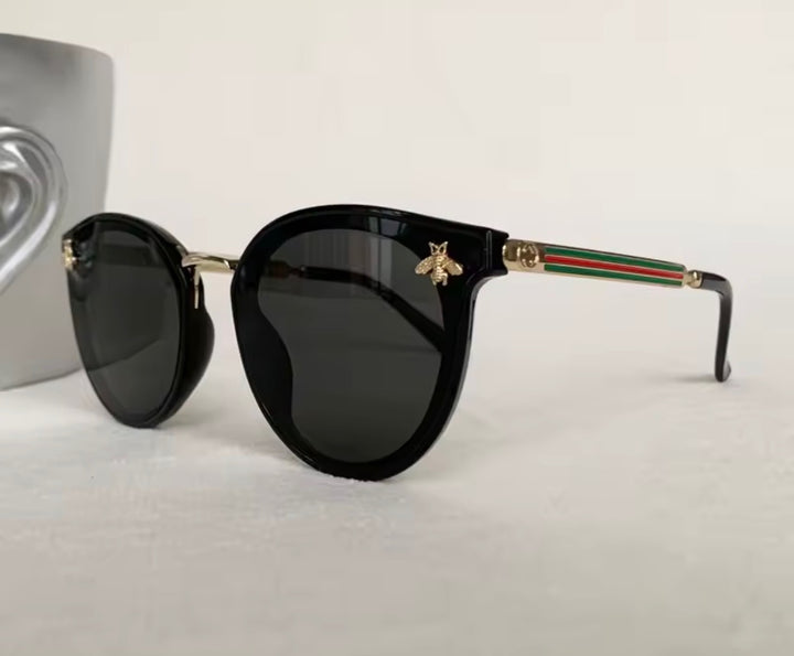 Black sunglasses with gold bee embellishment and green red stripe arms