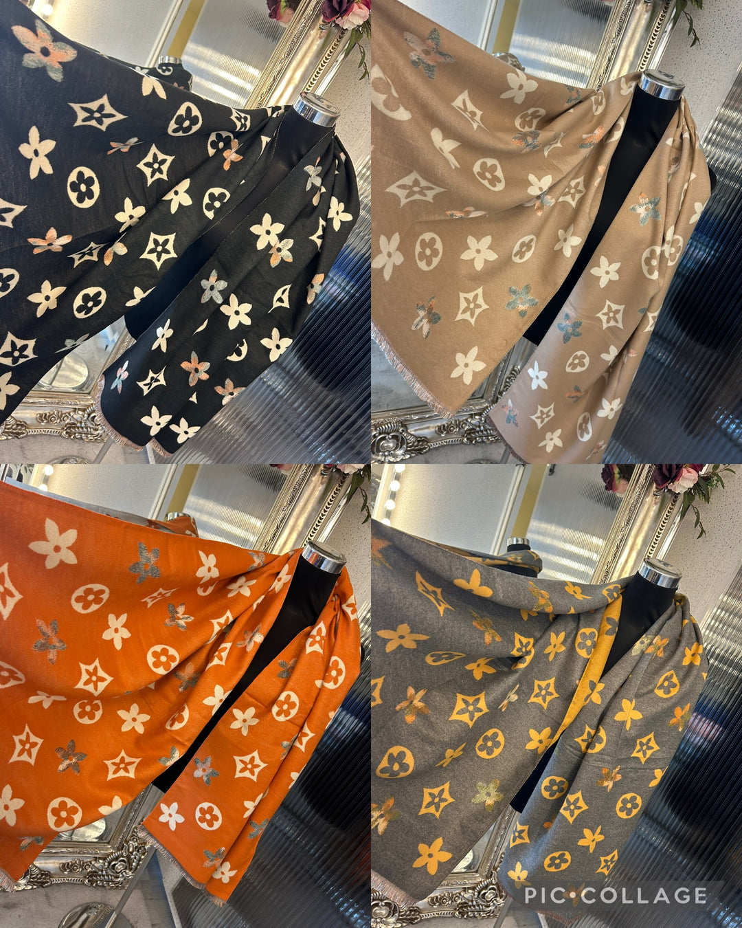 A collection of four multi-colored scarves with floral patterns displayed on a surface. The scarves are in black, brown, orange, and gray colors, each featuring a different floral design.