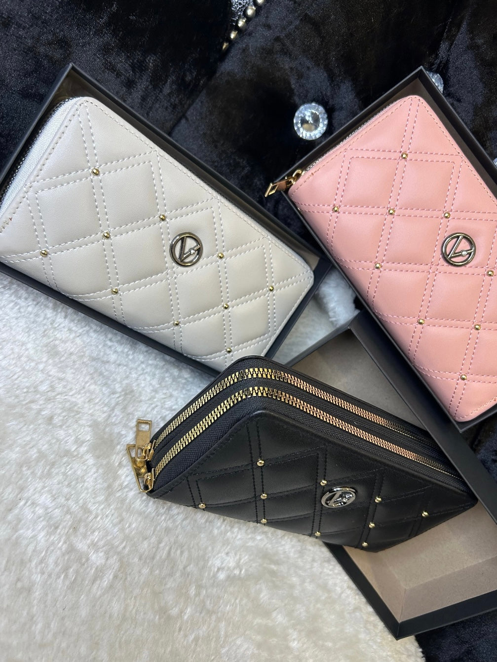 Three quilted leather purses in pink, white, and black, displayed side by side with zip compartments visible.