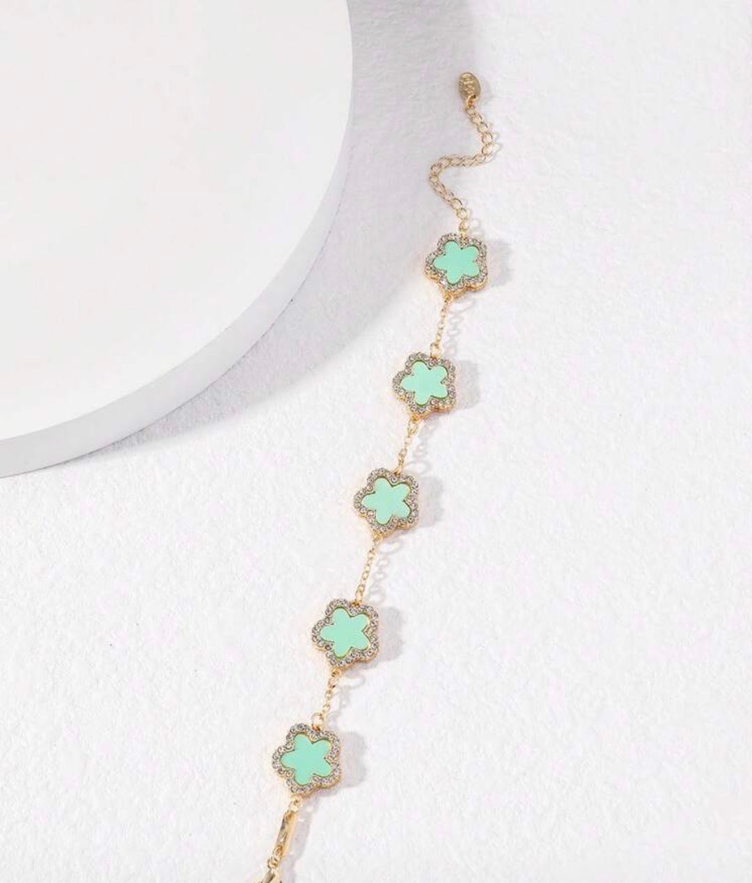     Adjustable gold bracelet with five mint clover charms and crystal detailing