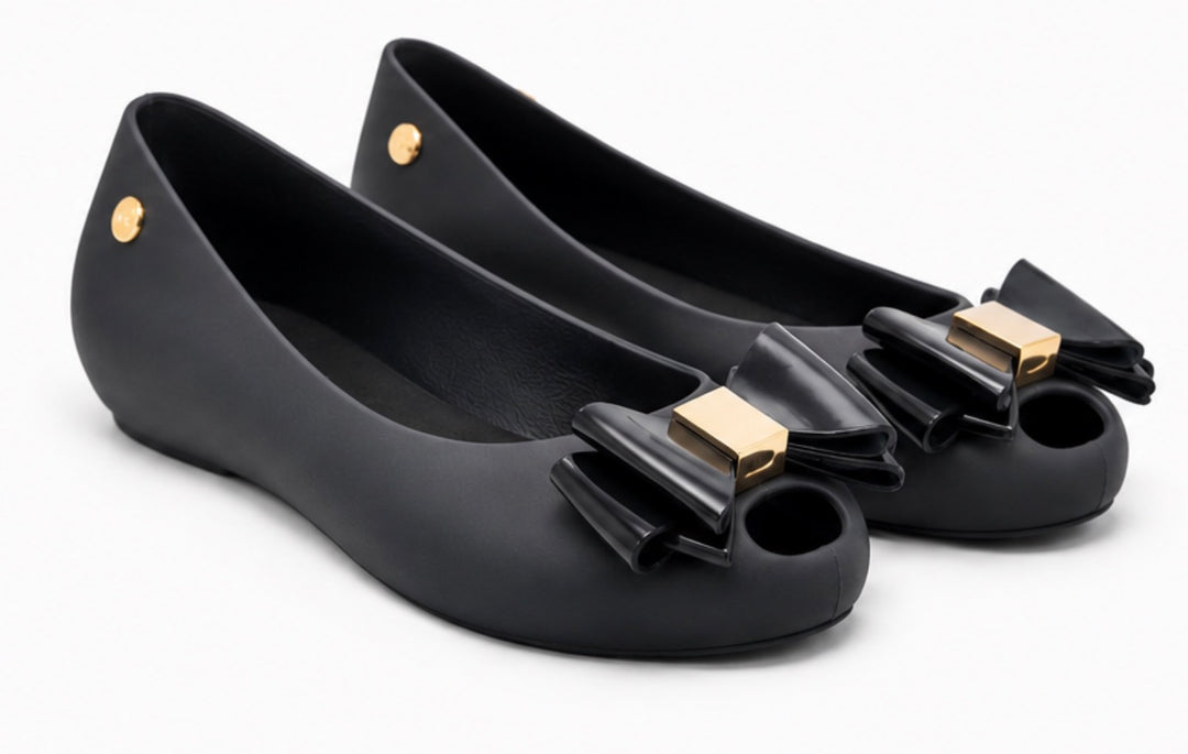 Women’s black jelly-style flats with decorative bow front