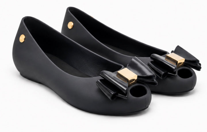 Women’s black jelly-style flats with decorative bow front