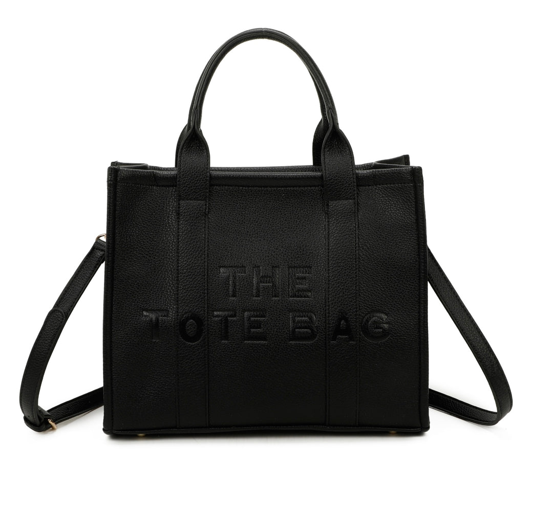 A black tote bag with embossed ‘The Tote Bag’ text, structured design with top handles and detachable shoulder strap