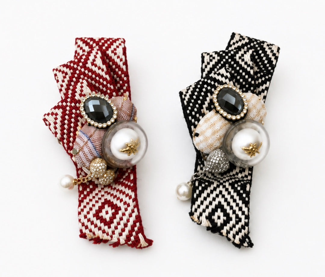 Red and black embellished fabric brooches featuring a crystal centre, faux pearl with gold bee detail and secure pin fastening