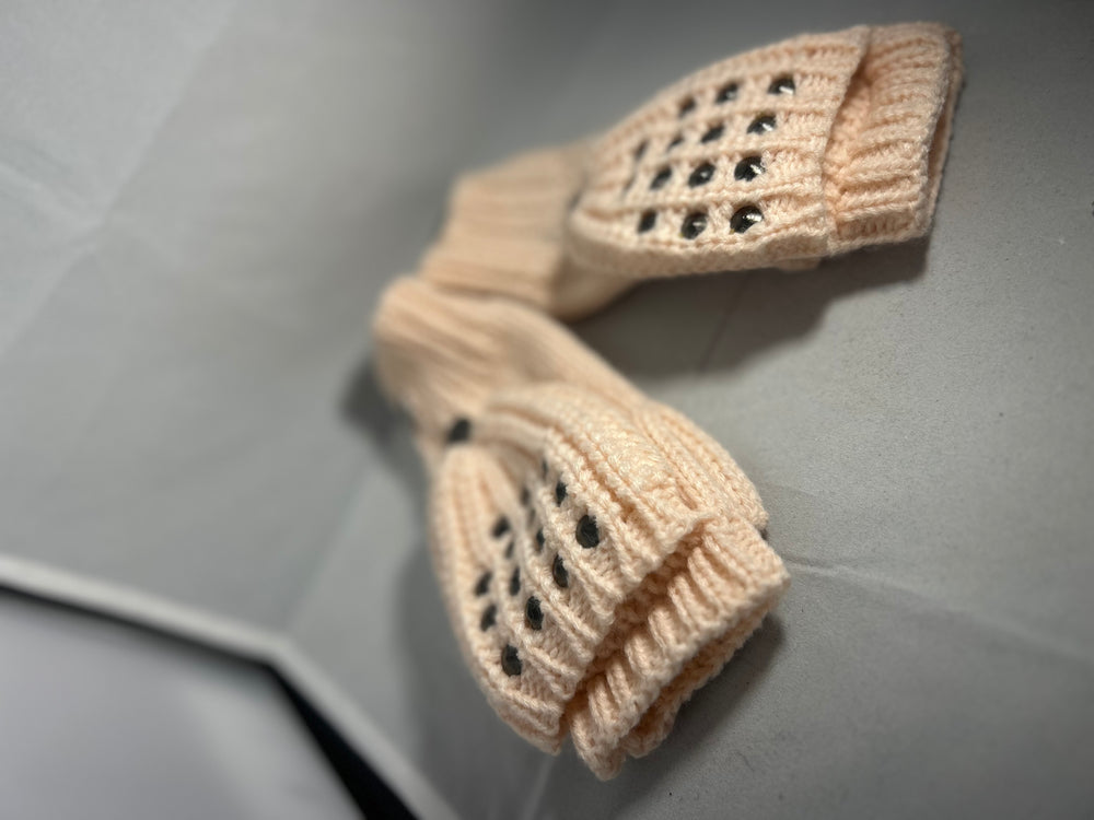 A pair of baby pink knitted mittens with stud patterns