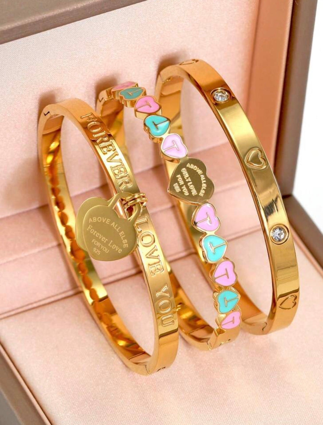     Gold three-piece stainless steel love bangle bracelet set with heart charms and crystal detailing.