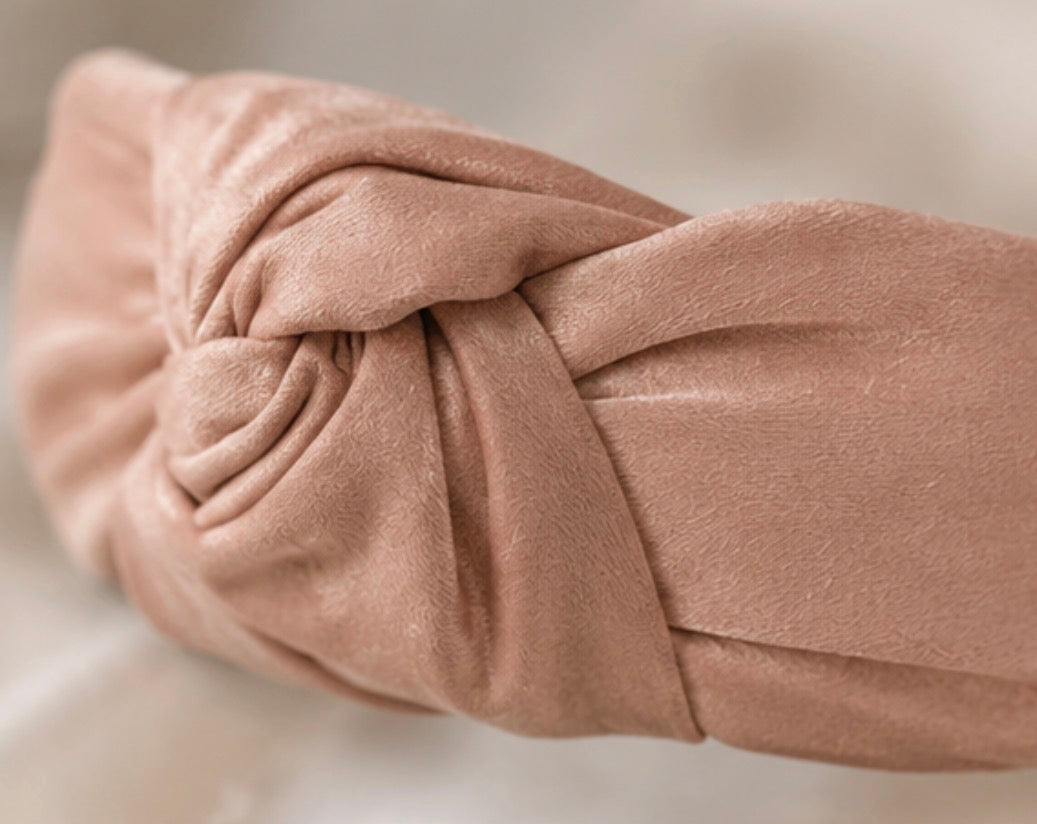 Soft pink satin knotted padded headband with elegant knot detail and comfortable design.