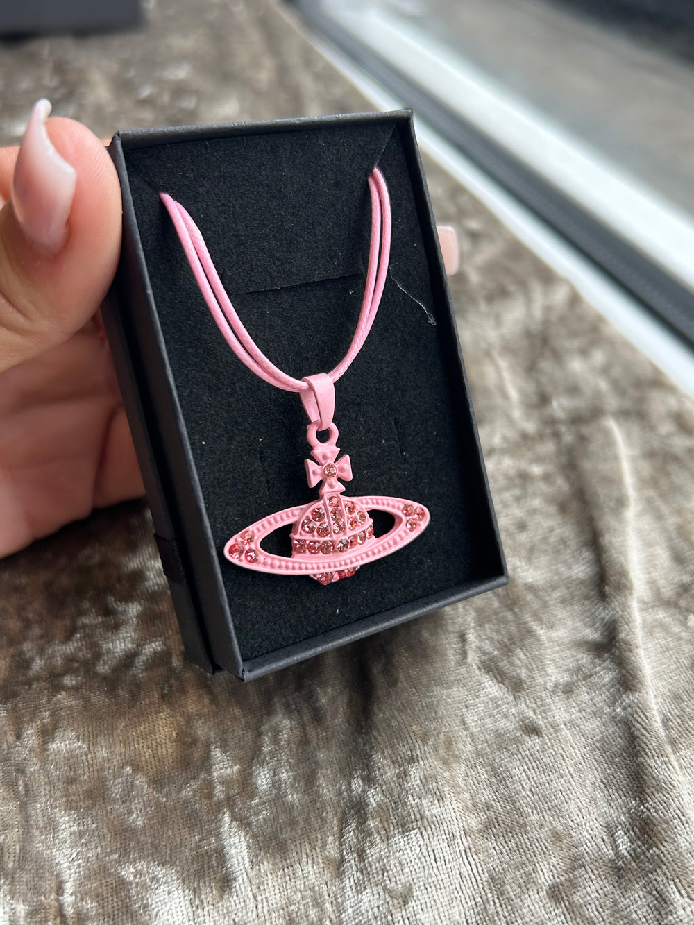 A pink rope necklace with a planet-shaped crystal pendant