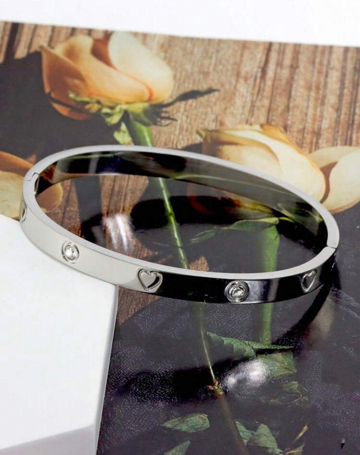 Silver three-piece stainless steel love bangle bracelet set with heart charms and crystal detailing.