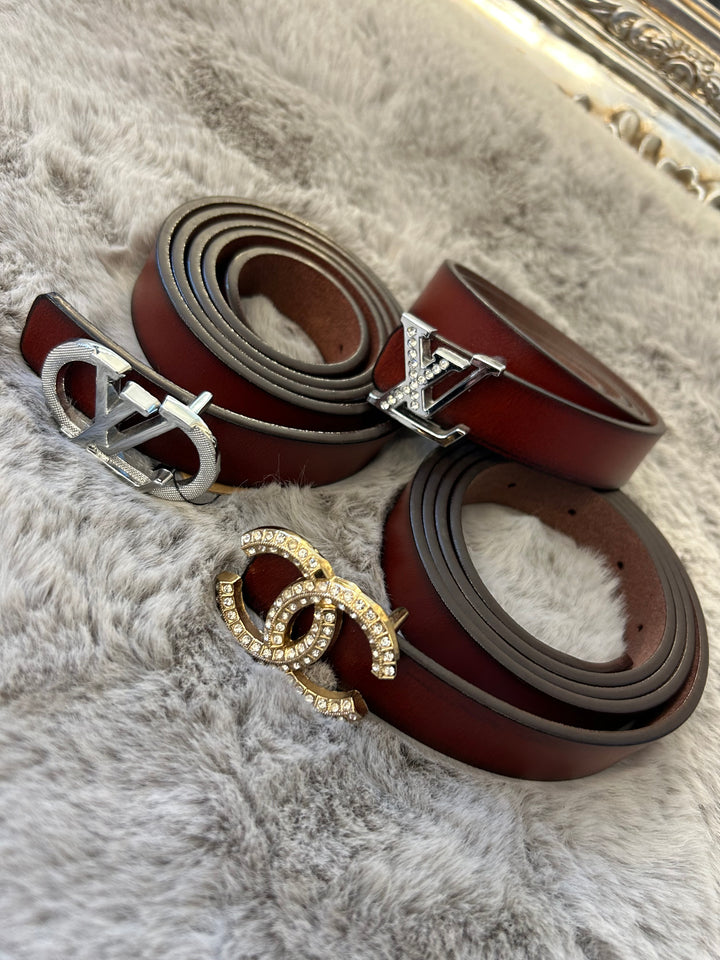 A collection of small brown belts with different buckles