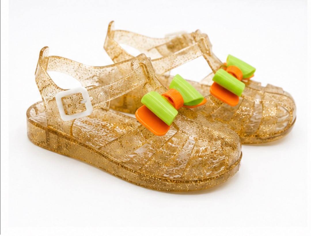 Girls colourful jelly sandals collection featuring yellow, black and glitter gold styles with decorative bows