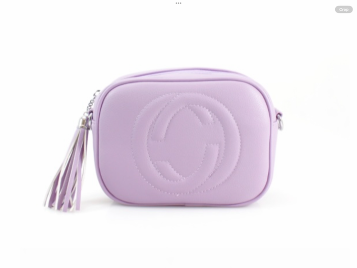 A lilac crossbody camera bag with embossed circle logo design, detachable strap and tassel zip detail