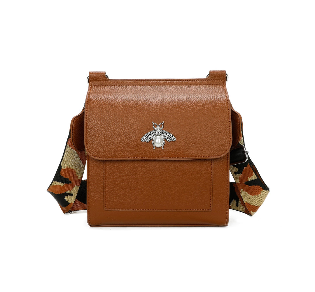 A tan satchel crossbody bag with a bee design on the front flap, featuring a camouflage pattern on the strap.