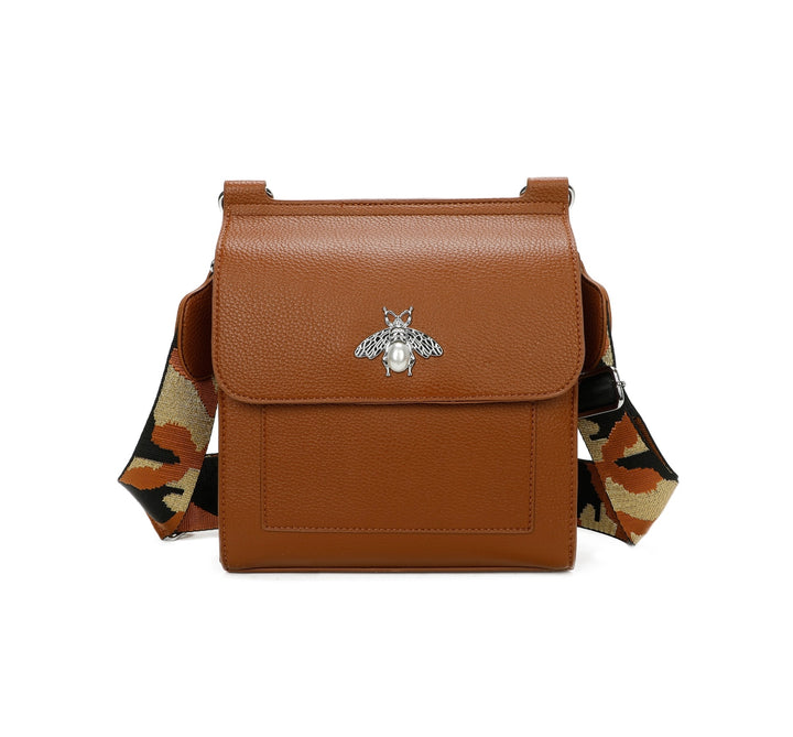 A tan satchel crossbody bag with a bee design on the front flap, featuring a camouflage pattern on the strap.