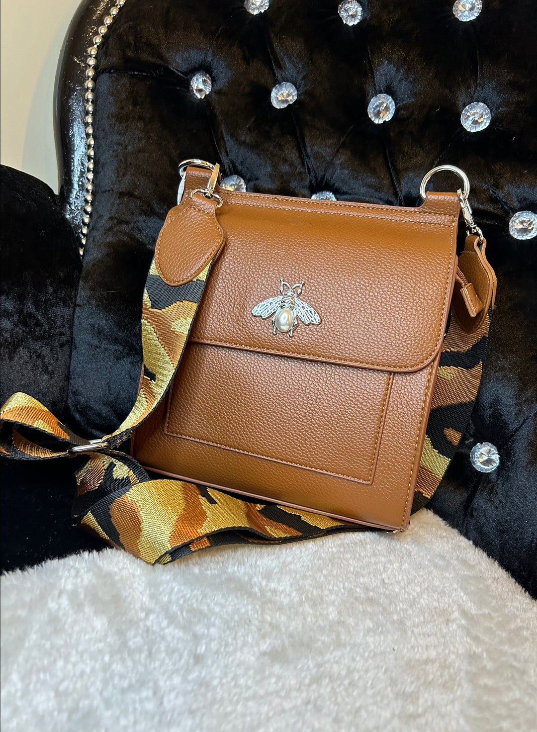 Tan crossbody bag with silver bee and pearl detail on flap, adjustable monochrome patterned straw