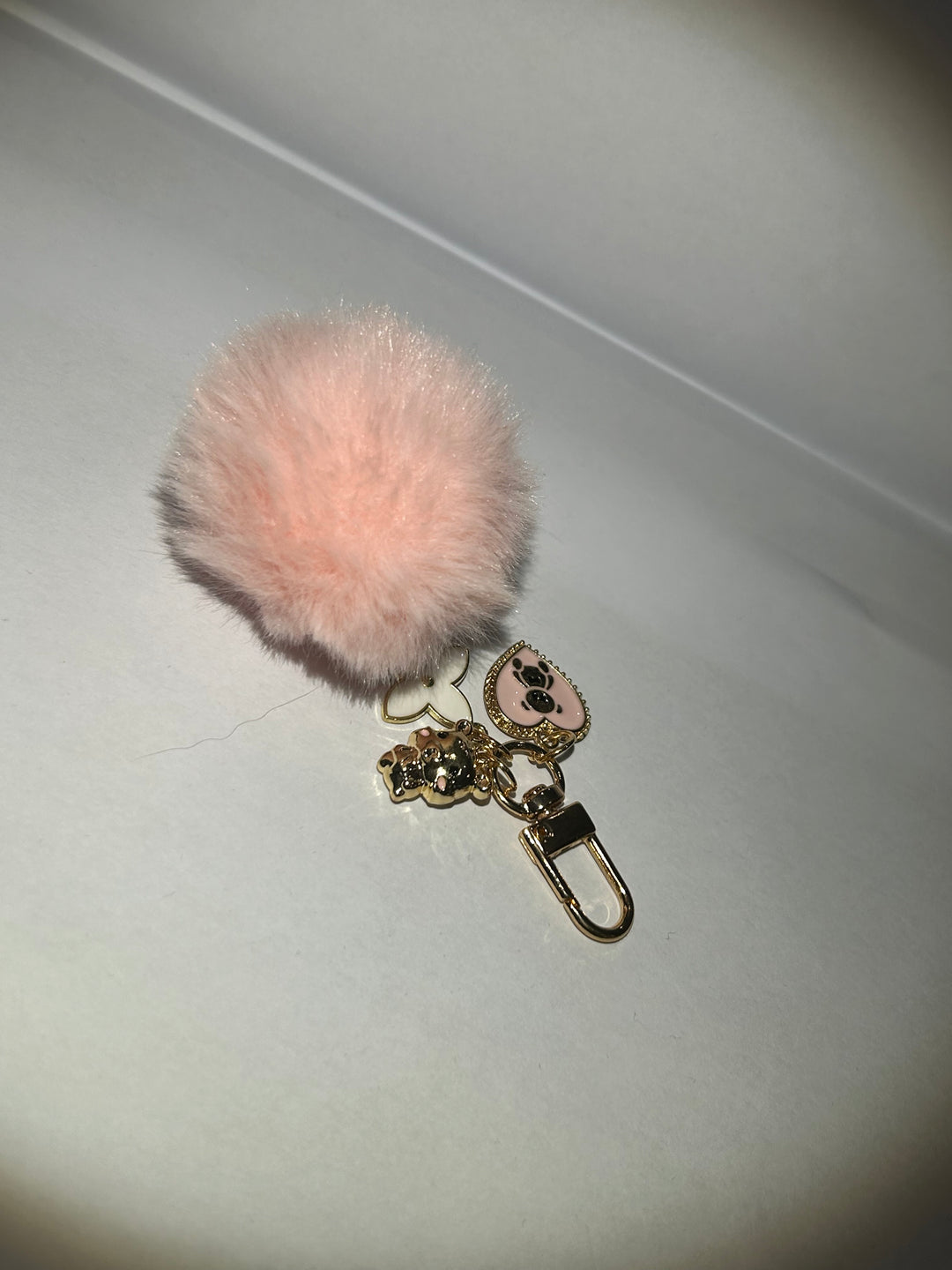 A pink clover flower key ring with a fluffy pom-pom and additional charms attached to it. back of charm