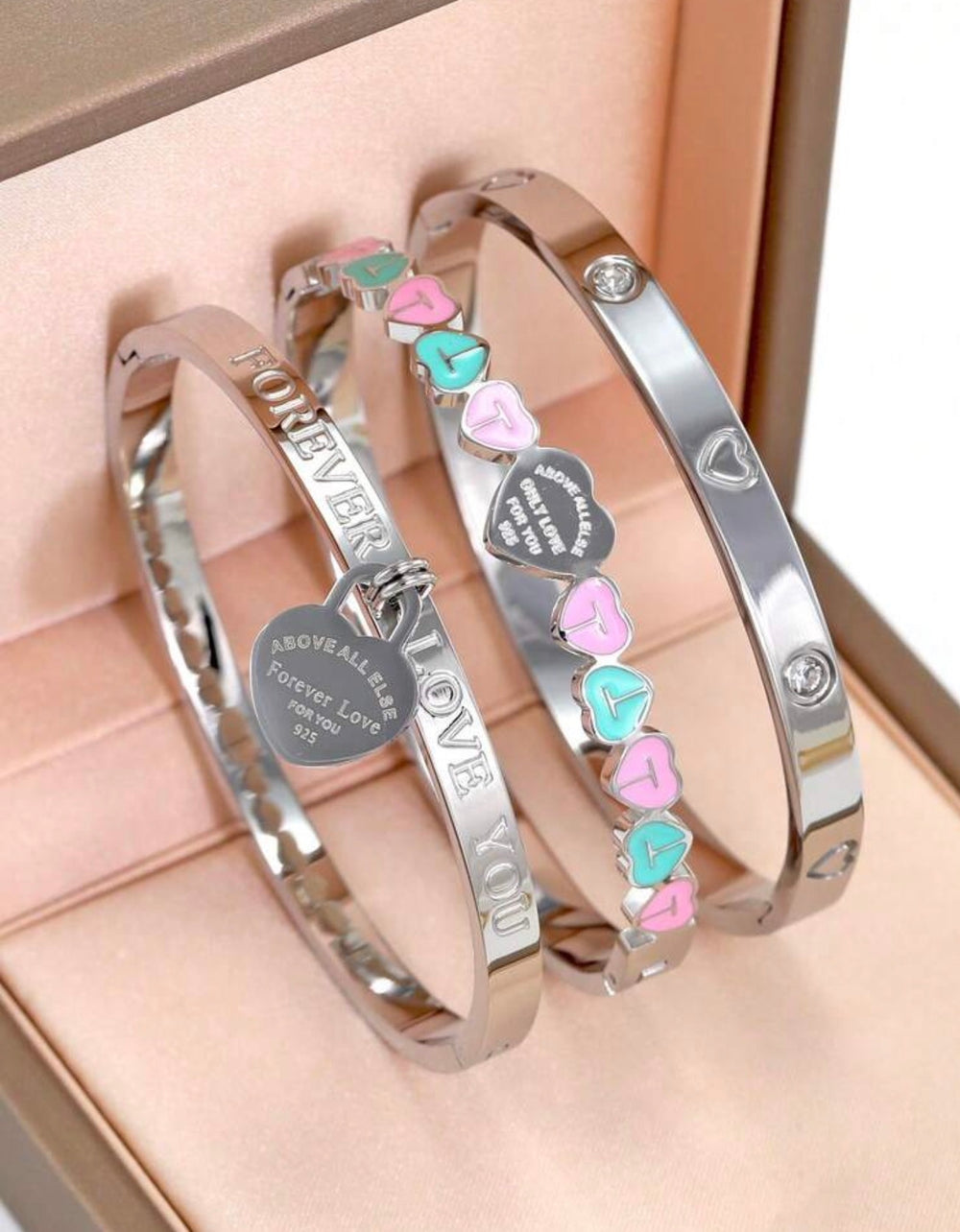 Silver three-piece stainless steel love bangle bracelet set with heart charms and crystal detailing.