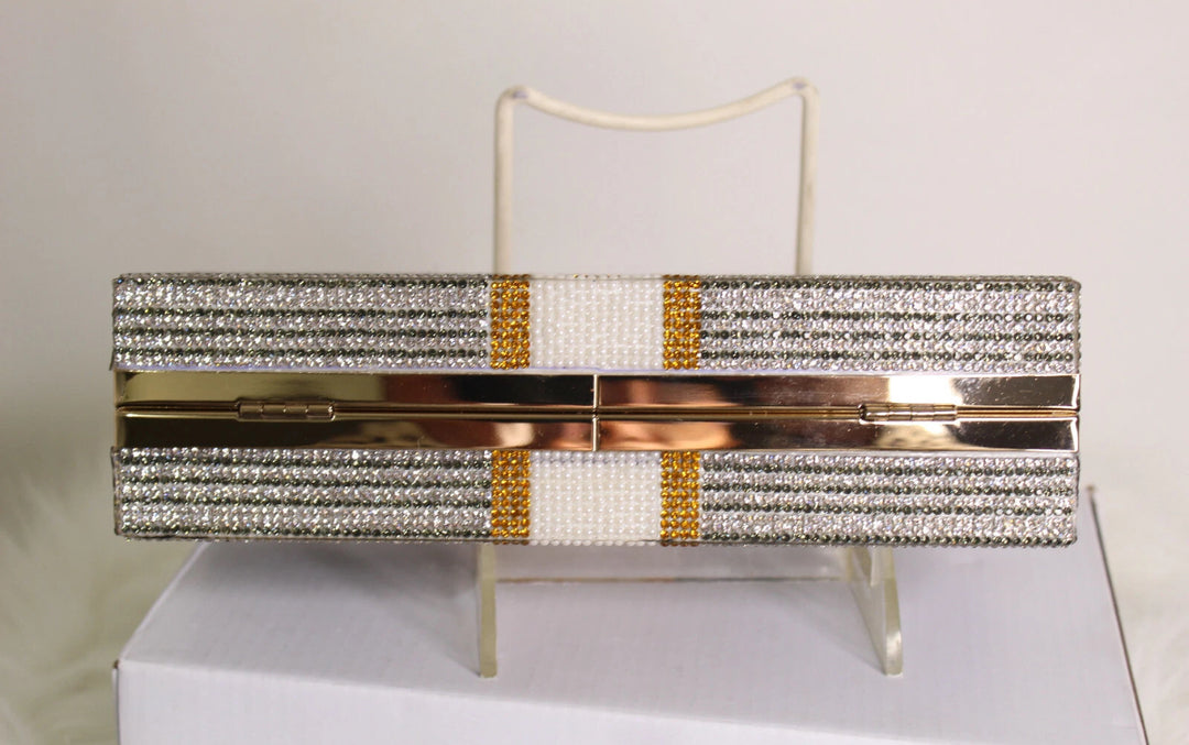 Sparkly clutch bag with gold accents on a stand against a light background