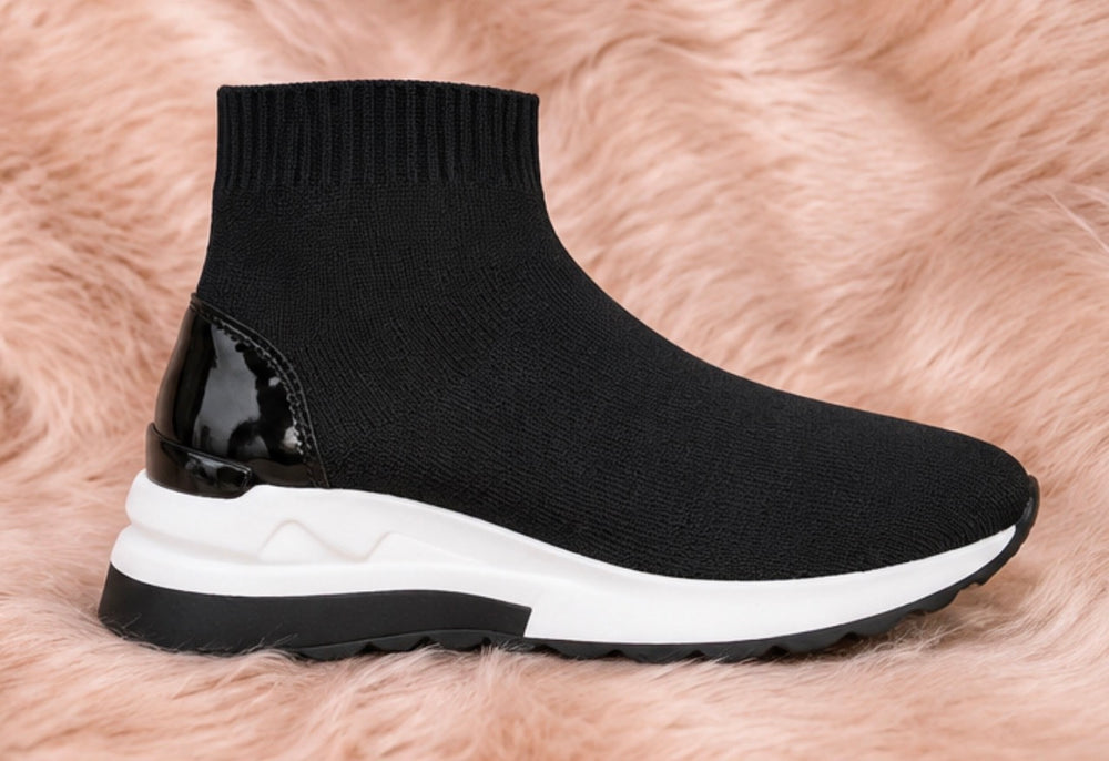 A pair of black and white slip-on trainers with a wedge sole.
