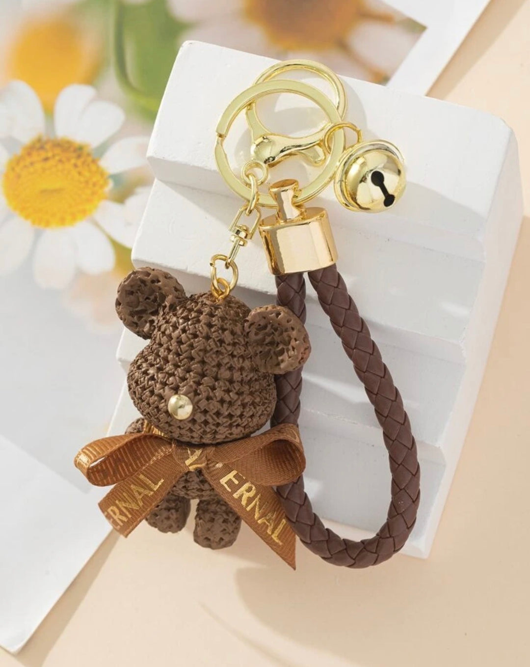     Brown teddy bear keyring with braided wrist strap and gold bell charm.