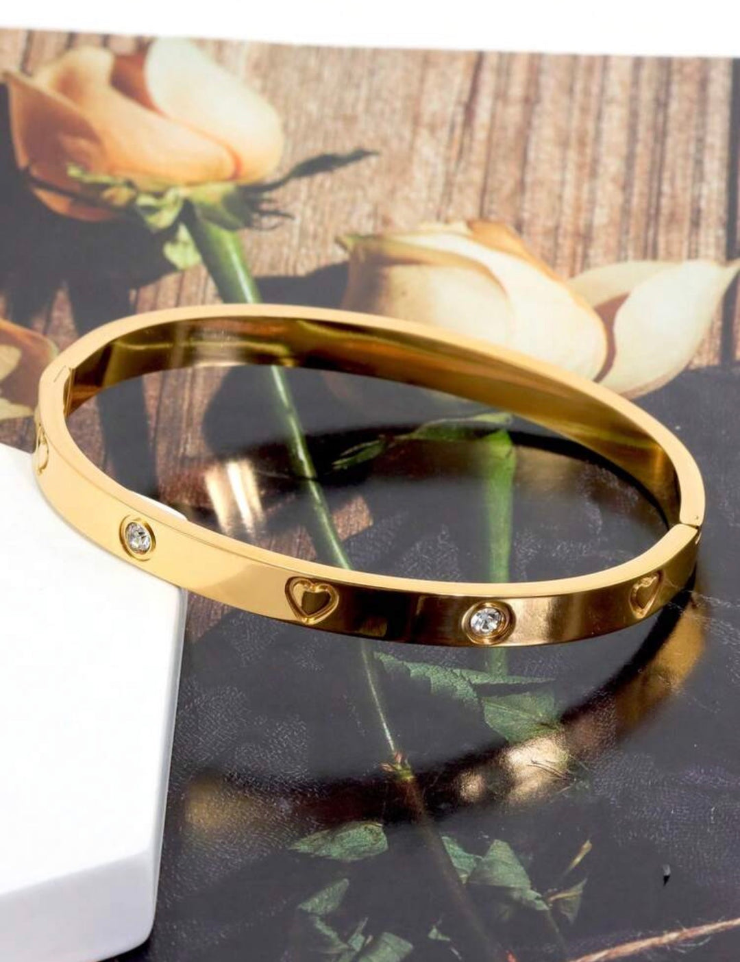 Gold  three-piece stainless steel love bangle bracelet set with heart charms and crystal detailing.