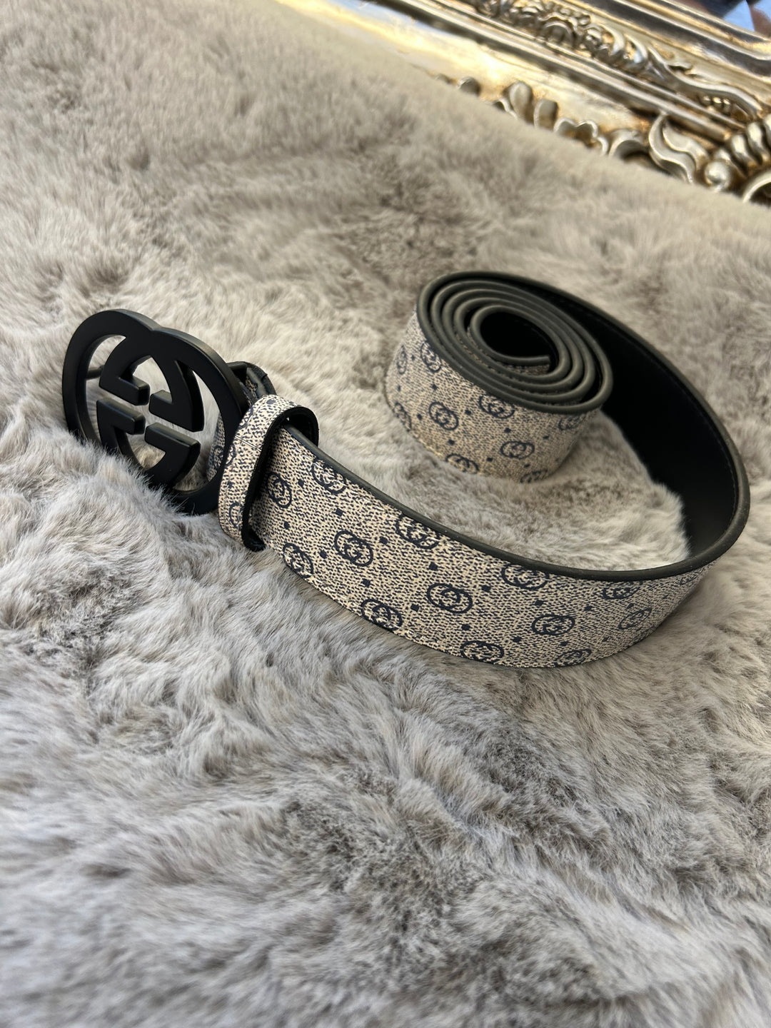A coiled grey and black belt with a patterned buckle