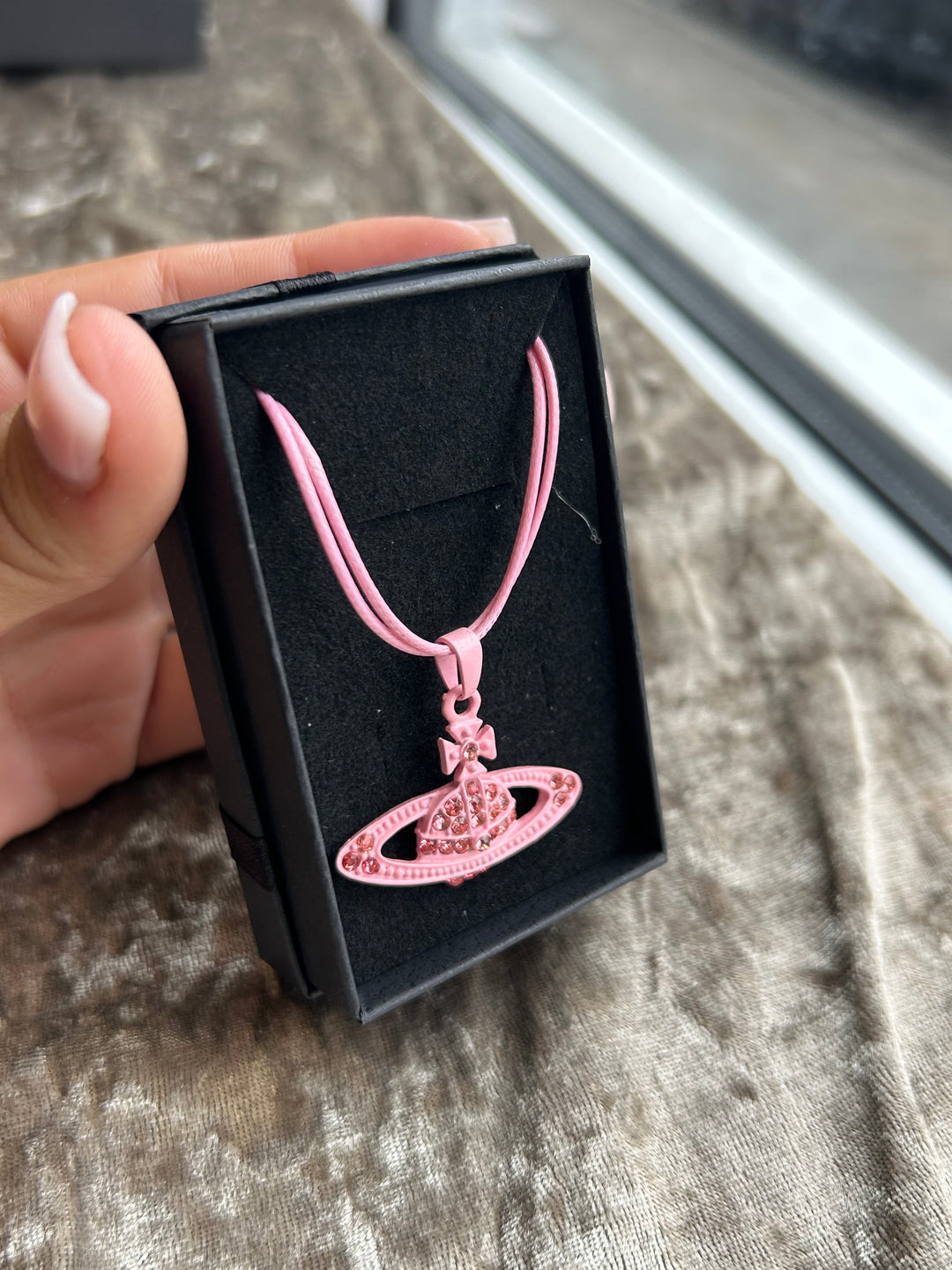 A pink rope necklace with a planet-shaped pendant
