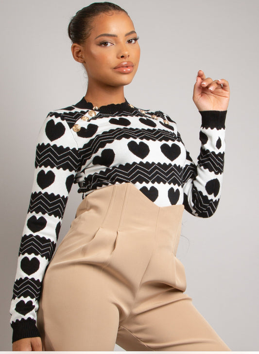 Woman wearing a black and white patterned sweater with beige high waisted trousers 