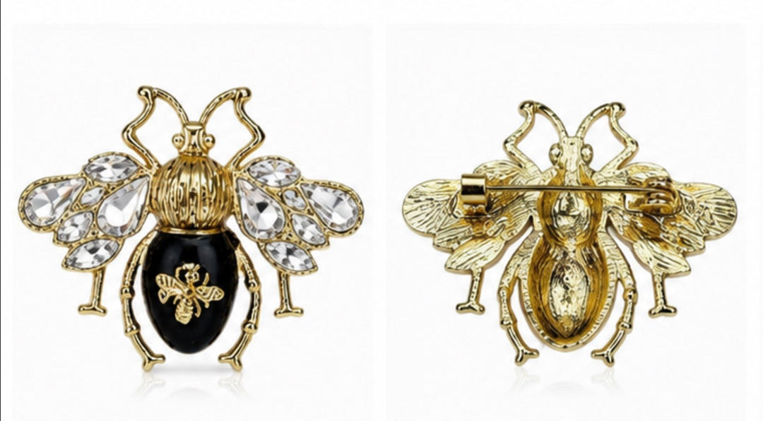 A gold-tone bee brooch shown from both front and back views on a white background. The front view features a black enamel abdomen and clear rhinestone wings, while the back view shows the pin's clasp mechanism.
