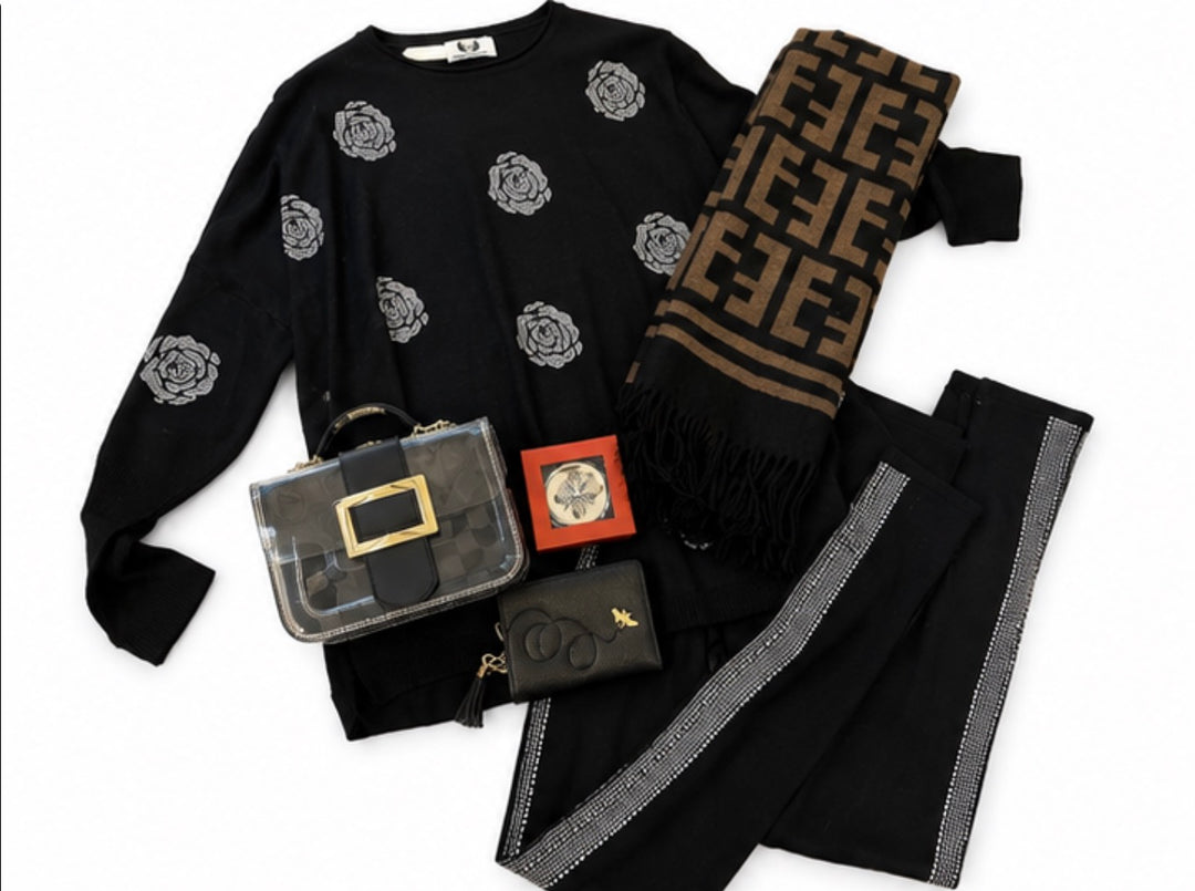Black two-piece lounge set featuring an oversized knitted top with sparkling rose embellishments and matching leggings with rhinestone side stripe detailing.