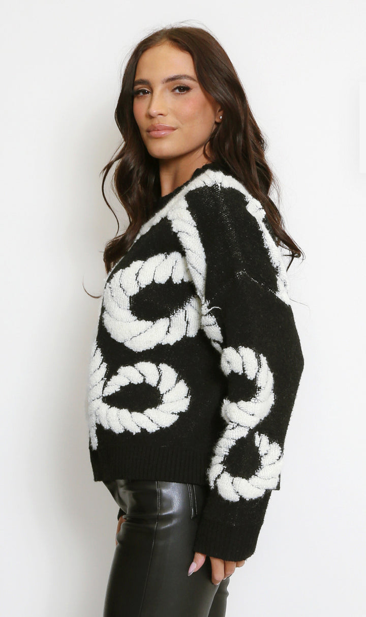Woman wearing a black and white patterned sweater side view