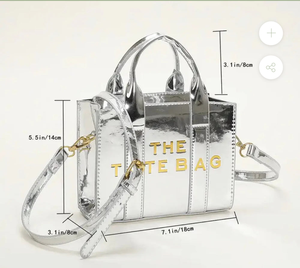 Small silver  handbag with 'THE TOTE BAG' text with a gold adjustable handle 