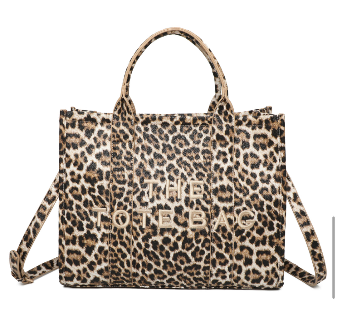 A leopard animal print tote bag with double grab straps and gold tone metal hardware.
