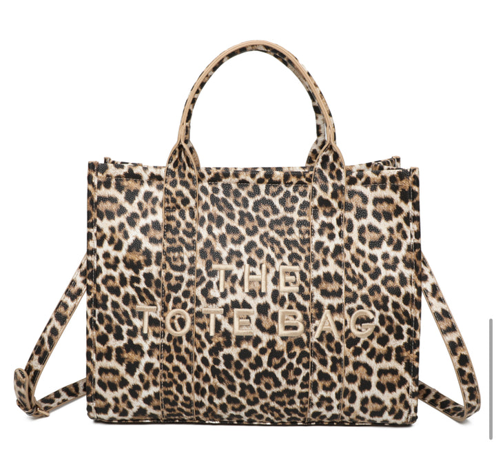 A leopard animal print tote bag with double grab straps and gold tone metal hardware.