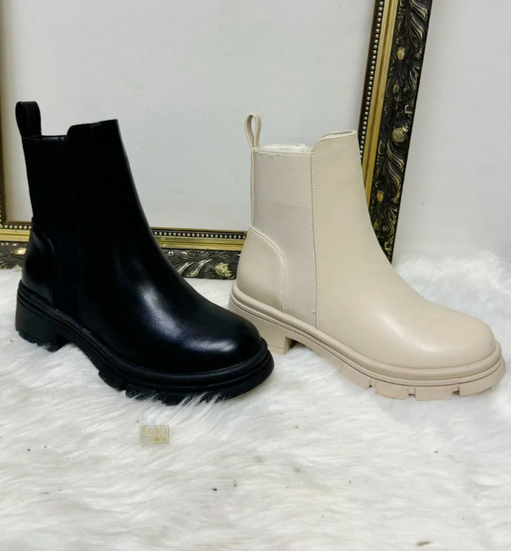 A pair of black ankle boots next to a pair of cream ankle boots 