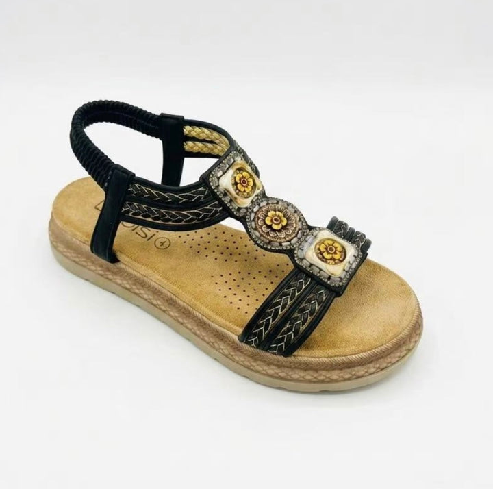 Black and gold sandal with decorative elements on a white background