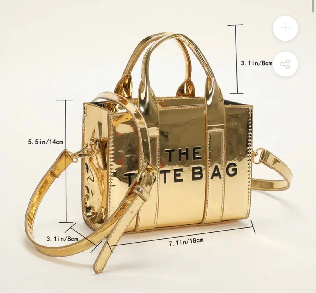 Small Gold handbag with 'THE TOTE BAG' text with a gold adjustable handle 