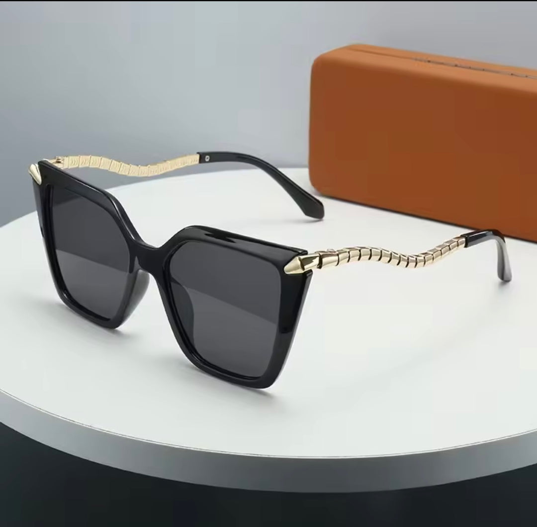 Luxury black oversized square sunglasses with gold textured arms displayed on a white background.