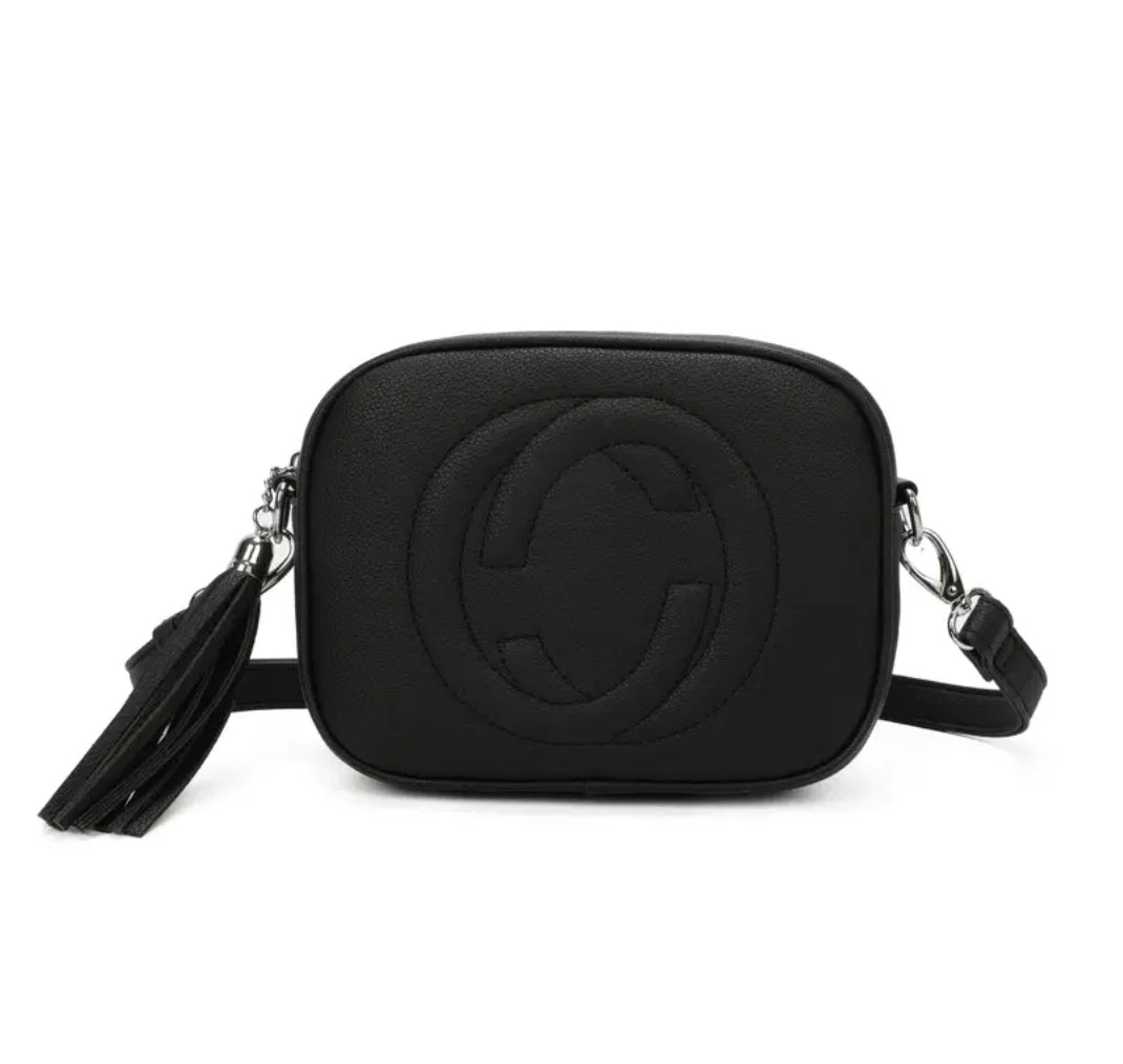 A black crossbody camera bag with embossed circle logo design, detachable strap and tassel zip detail