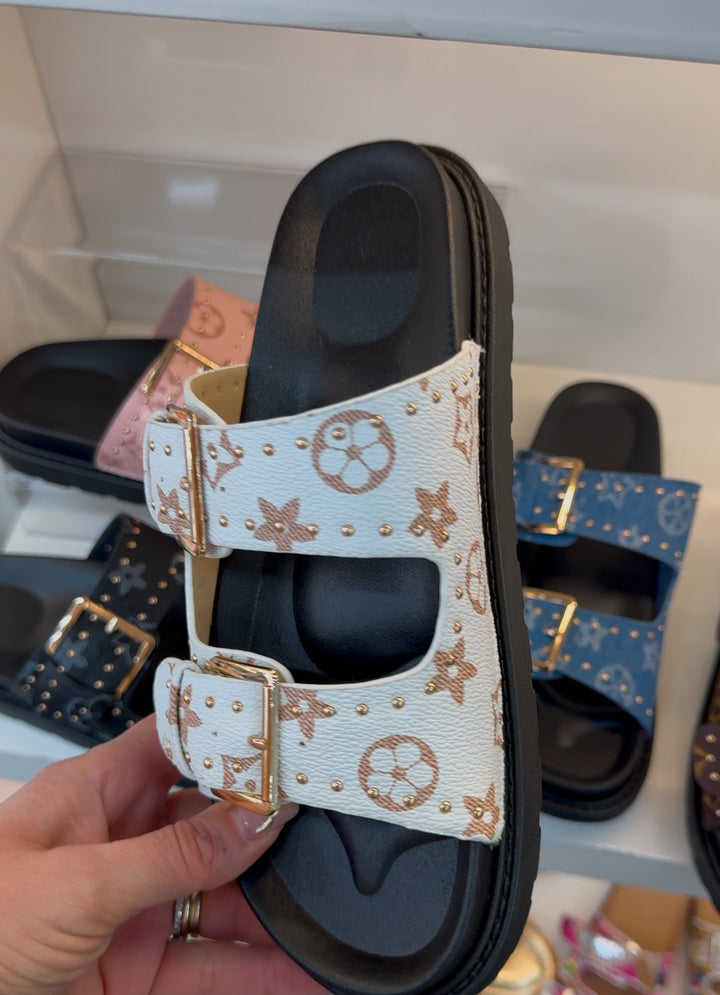 White sliders with flower detail and a black sole 