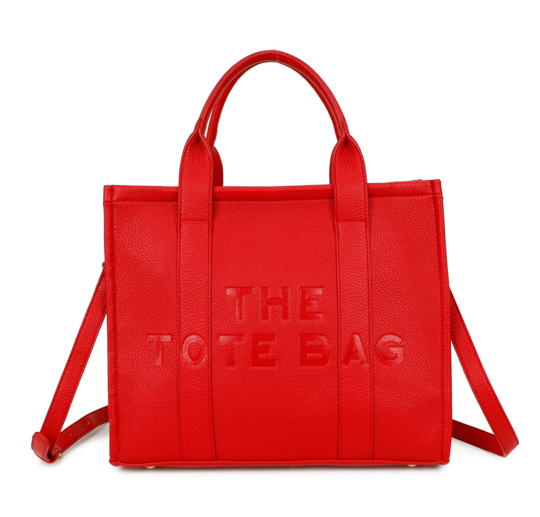 A red tote bag with embossed ‘The Tote Bag’ text, structured design with top handles and detachable shoulder strap